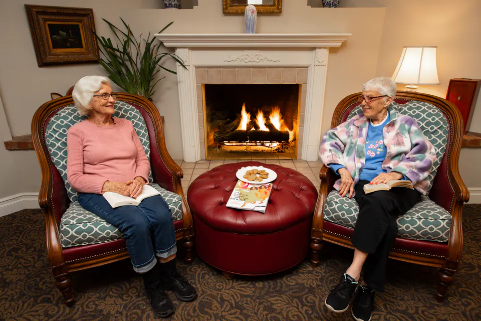 Residents relaxing with books and conversation by the fireplace